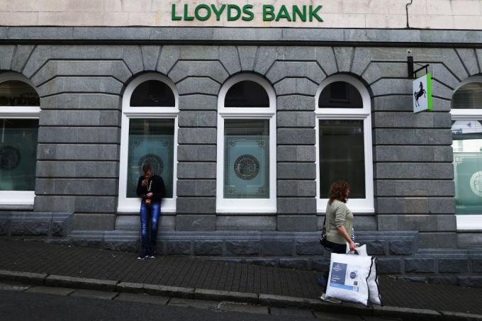 여성은 건지섬에서 영국 은행, 로이드 은행을 지나 걷습니다